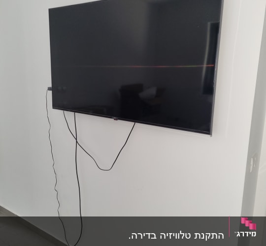 טלוויזיה מותקנת על קיר עם כבלים תלויים